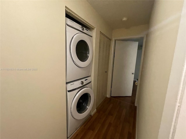 washroom with laundry area, stacked washer / dryer, and dark wood-type flooring