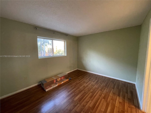 unfurnished room featuring wood finished floors, baseboards, and a textured ceiling