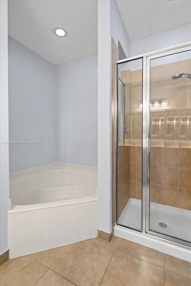 full bathroom featuring tile patterned flooring, a shower stall, and a bath