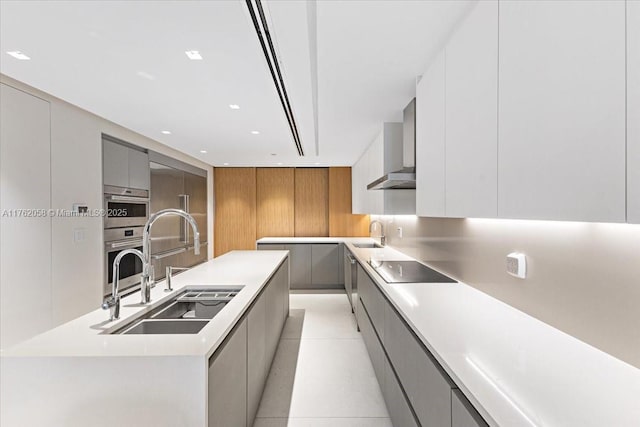 kitchen featuring wall chimney exhaust hood, modern cabinets, gray cabinets, and a sink