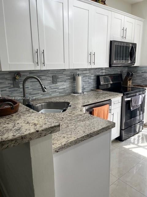 kitchen with light stone countertops, a sink, stainless steel range with electric stovetop, white cabinetry, and backsplash