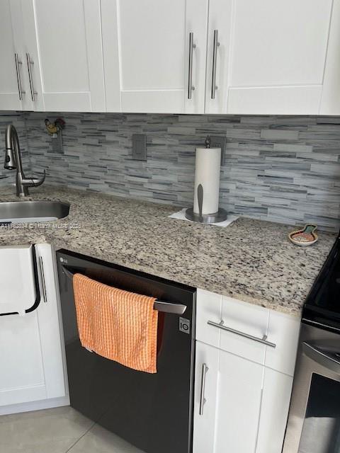 kitchen with dishwasher, white cabinetry, and a sink