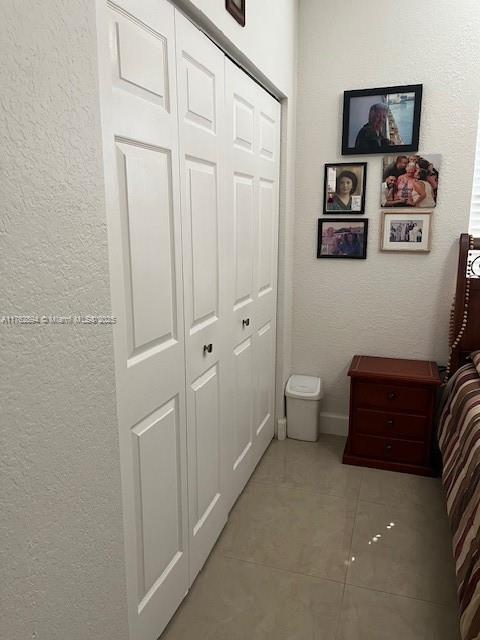 hall featuring light tile patterned flooring and a textured wall