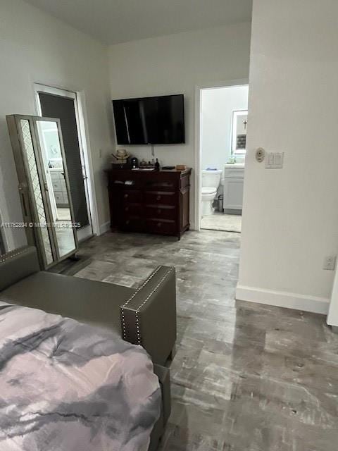 bedroom featuring ensuite bath, baseboards, and concrete flooring