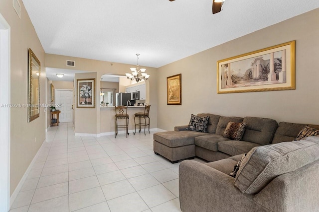 living room featuring visible vents, baseboards, light tile patterned floors, ceiling fan with notable chandelier, and arched walkways