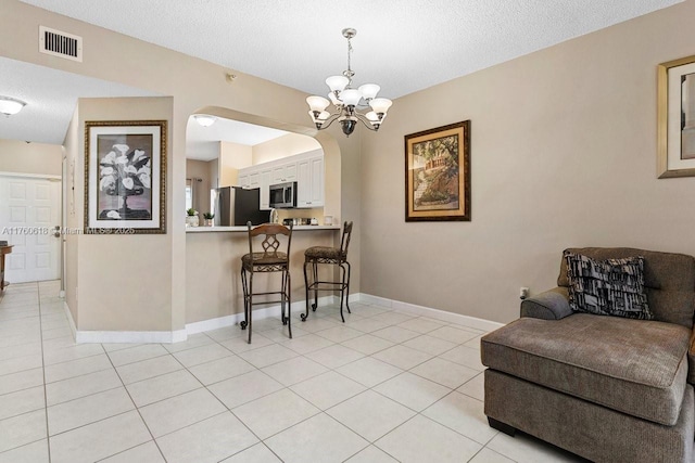 dining area with light tile patterned floors, visible vents, arched walkways, and baseboards