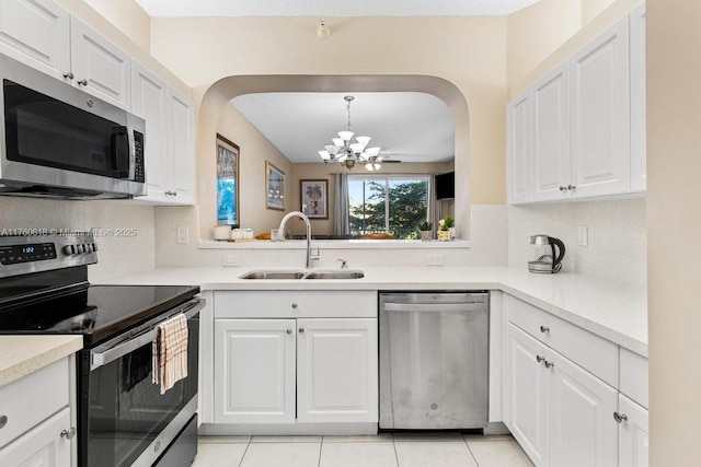 kitchen with backsplash, a chandelier, appliances with stainless steel finishes, white cabinetry, and a sink