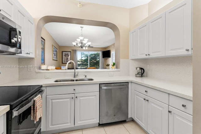 kitchen featuring a chandelier, decorative backsplash, white cabinets, stainless steel appliances, and a sink