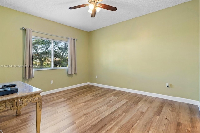 spare room with a textured ceiling, light wood-style floors, baseboards, and ceiling fan