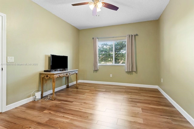 interior space featuring a textured ceiling, a ceiling fan, light wood-type flooring, and baseboards