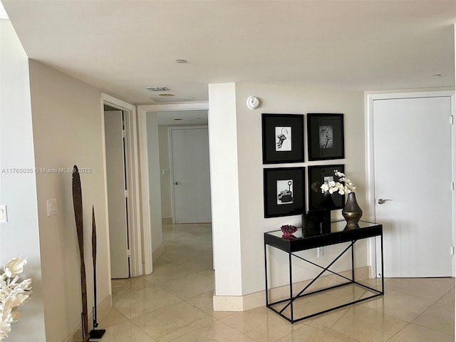 corridor featuring light tile patterned floors and baseboards