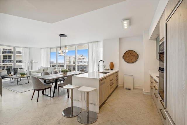 kitchen featuring open floor plan, a peninsula, light countertops, and a sink