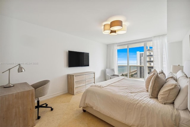 bedroom featuring baseboards and expansive windows