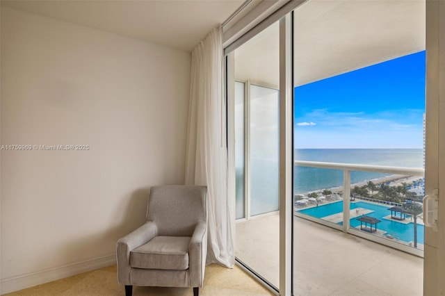 sitting room featuring floor to ceiling windows, baseboards, and a water view