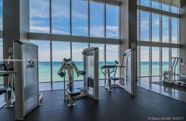 exercise room with expansive windows and a water view