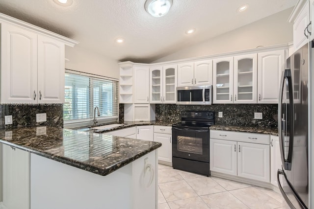 kitchen featuring lofted ceiling, a peninsula, white cabinets, stainless steel appliances, and a sink