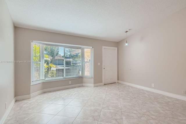 spare room featuring lofted ceiling, baseboards, and a textured ceiling