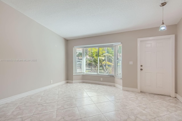 spare room with baseboards and a textured ceiling