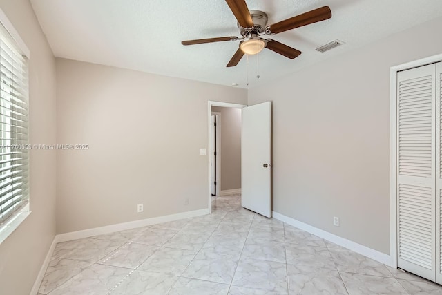 unfurnished bedroom with visible vents, marble finish floor, a closet, baseboards, and ceiling fan