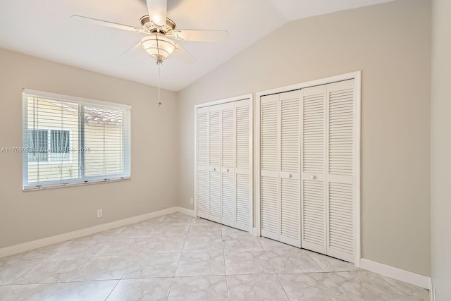 unfurnished bedroom featuring baseboards, lofted ceiling, two closets, and a ceiling fan