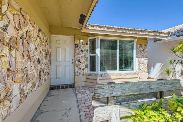 property entrance featuring stucco siding and stone siding