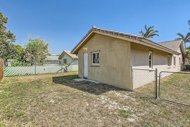 view of home's exterior featuring a gate, stucco siding, a yard, and fence