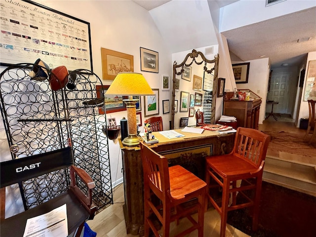 dining area with visible vents, wood finished floors, and vaulted ceiling