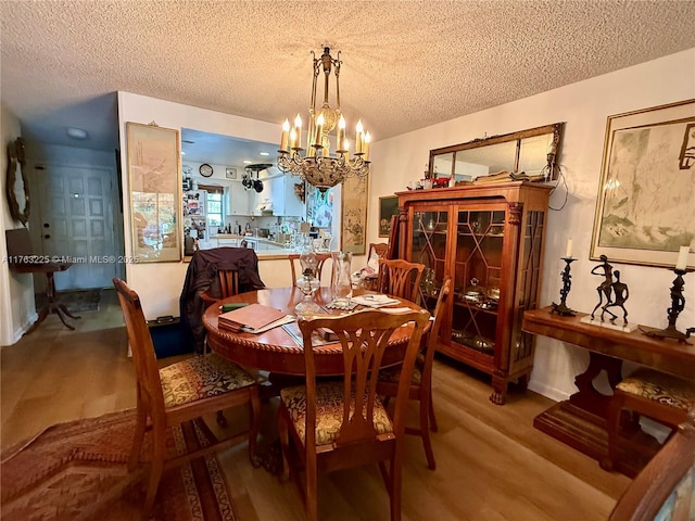 dining area featuring light wood-style floors, a chandelier, and a textured ceiling