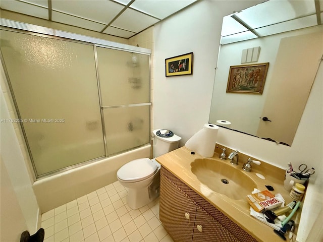 bathroom featuring toilet, combined bath / shower with glass door, tile patterned flooring, a paneled ceiling, and vanity