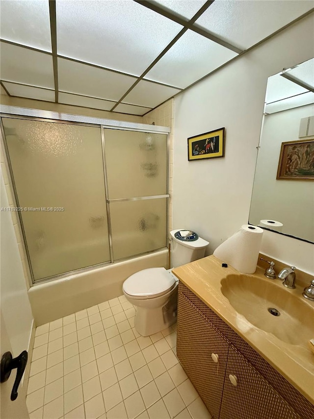 full bath featuring tile patterned floors, toilet, vanity, and bath / shower combo with glass door