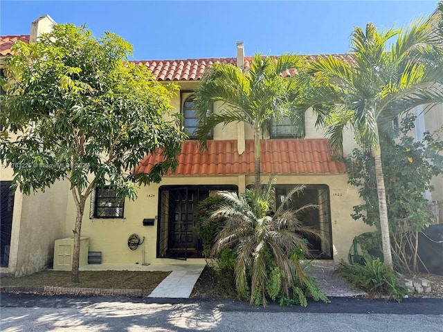 mediterranean / spanish home featuring a tiled roof and stucco siding