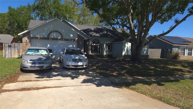 ranch-style house with brick siding, fence, concrete driveway, a front yard, and a garage