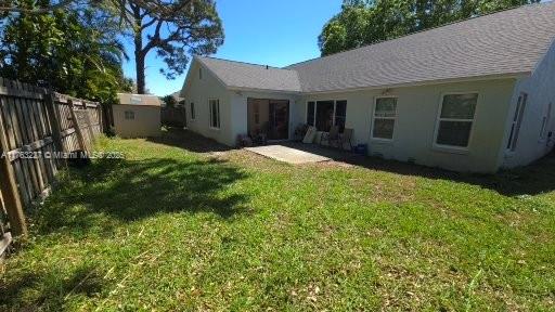 rear view of property featuring stucco siding, an outbuilding, a lawn, and a fenced backyard