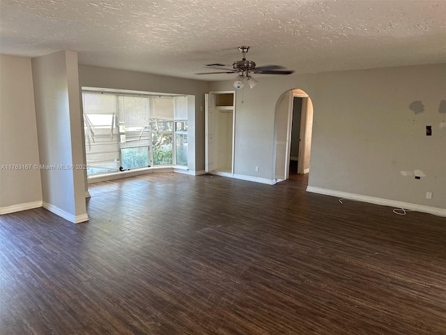 empty room with arched walkways, baseboards, ceiling fan, and dark wood-style flooring