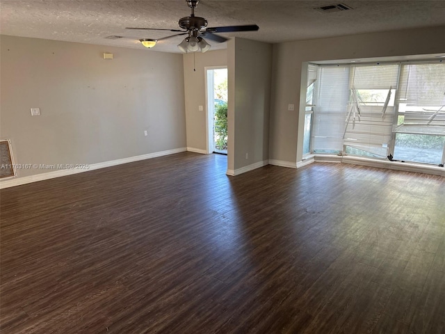 unfurnished room featuring dark wood-style floors, visible vents, baseboards, and a ceiling fan