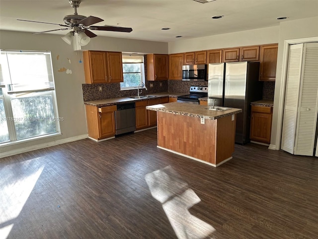 kitchen featuring a sink, appliances with stainless steel finishes, dark wood-style floors, and a center island