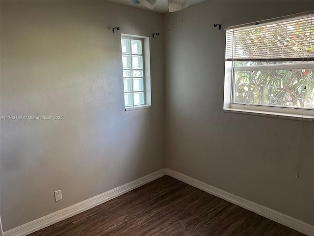 unfurnished room featuring baseboards, dark wood-style flooring, and ceiling fan