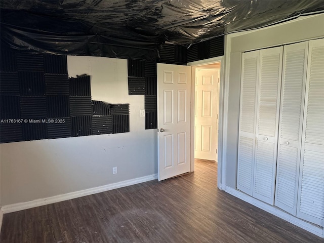 unfurnished bedroom featuring a closet, baseboards, and wood finished floors