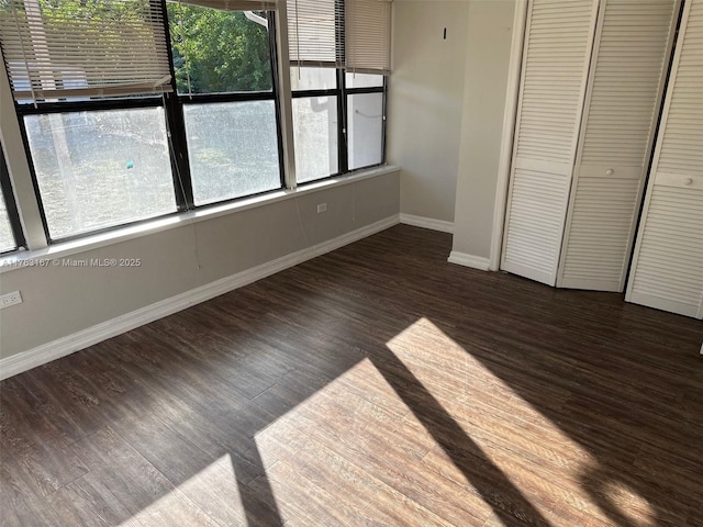 unfurnished bedroom with a closet, baseboards, and wood finished floors