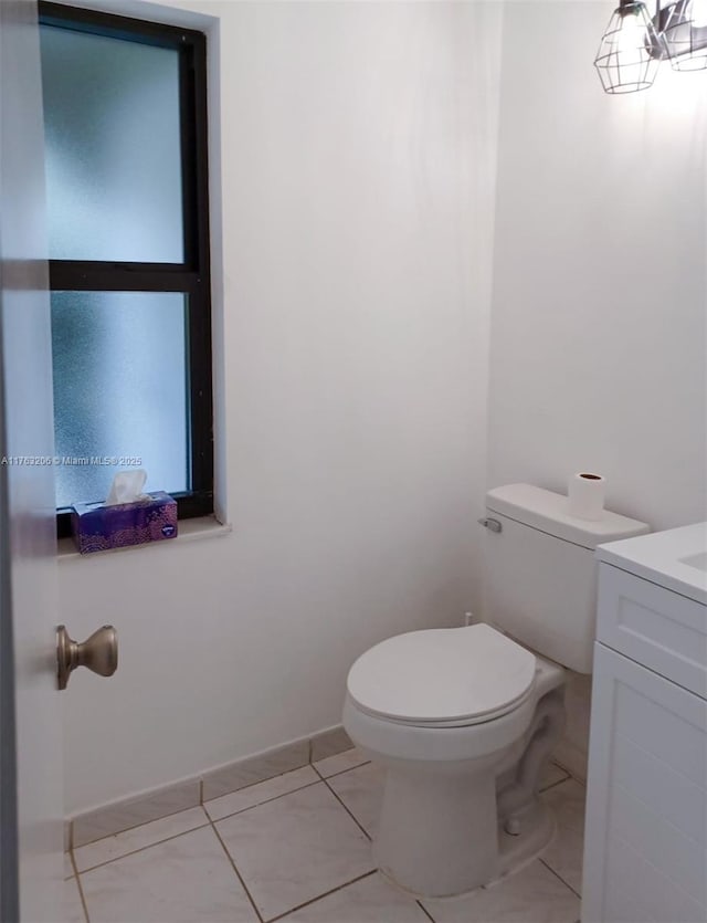 half bathroom featuring tile patterned flooring, toilet, vanity, and baseboards