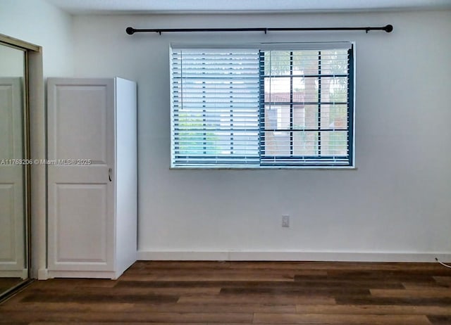 empty room featuring dark wood finished floors and baseboards