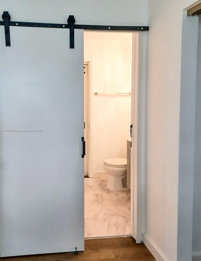 bathroom featuring toilet, wood finished floors, and baseboards