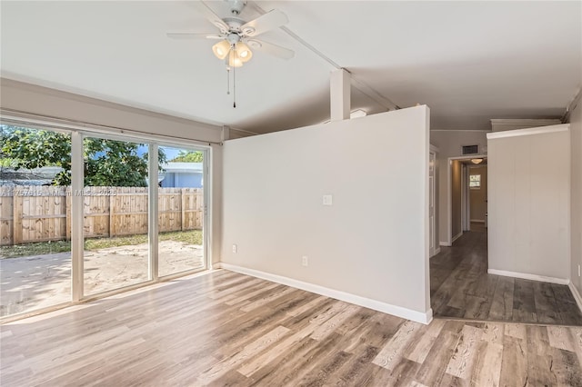 spare room featuring a ceiling fan, visible vents, wood finished floors, and baseboards