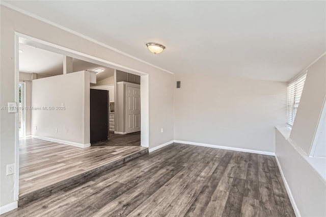 empty room featuring crown molding, wood finished floors, and baseboards