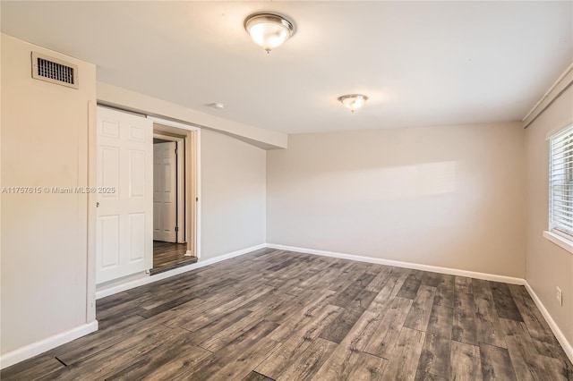 spare room featuring visible vents, baseboards, and dark wood finished floors