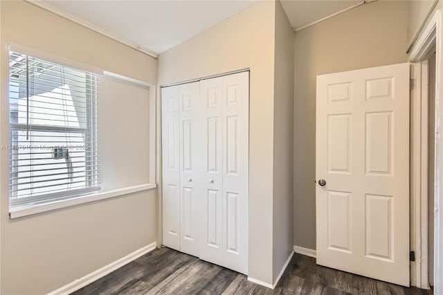 unfurnished bedroom featuring dark wood-type flooring, baseboards, and a closet