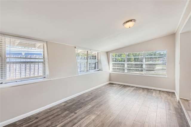 spare room with lofted ceiling, wood finished floors, and baseboards