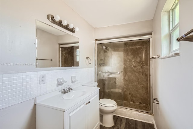 full bathroom featuring toilet, a stall shower, wood finished floors, tile walls, and vanity