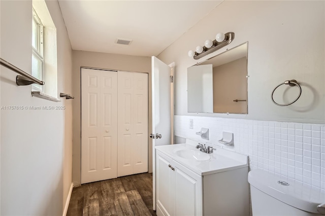 bathroom featuring visible vents, tile walls, toilet, wood finished floors, and vanity