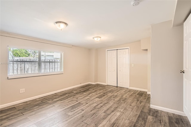 unfurnished bedroom featuring a closet, baseboards, and wood finished floors